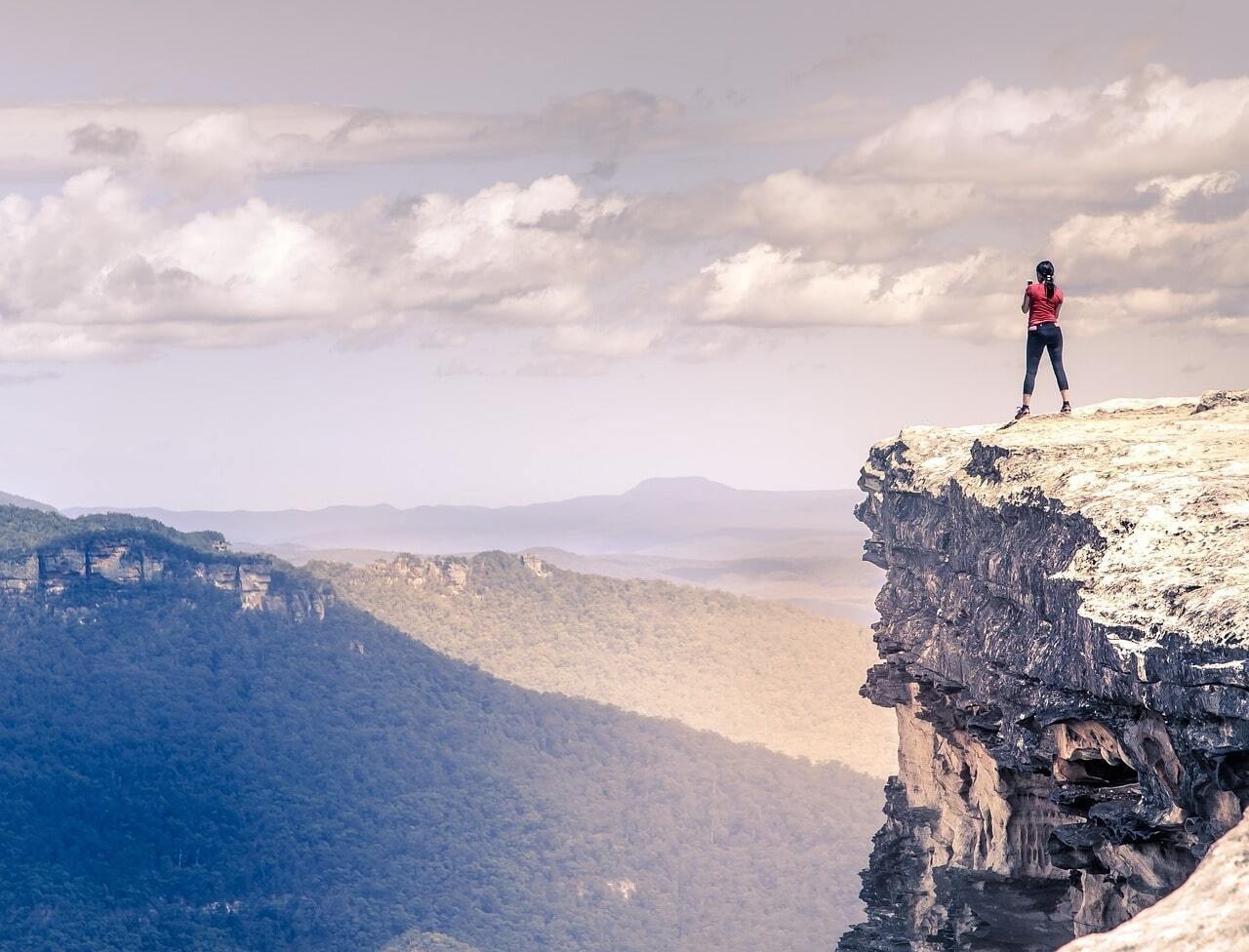 woman on top of cliff looking out across mountain range image
