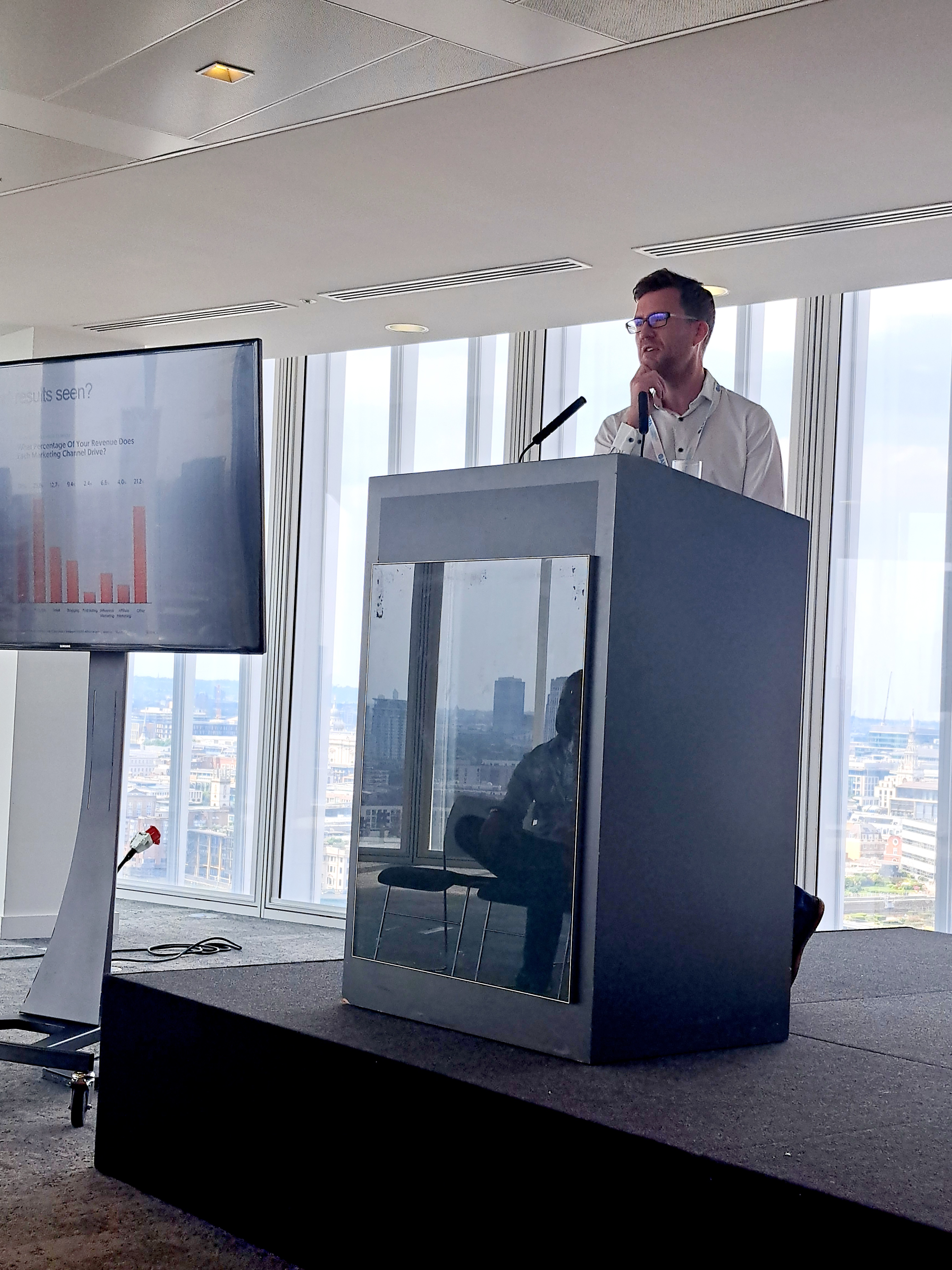 Man on stage presenting to a large group of peoplw image