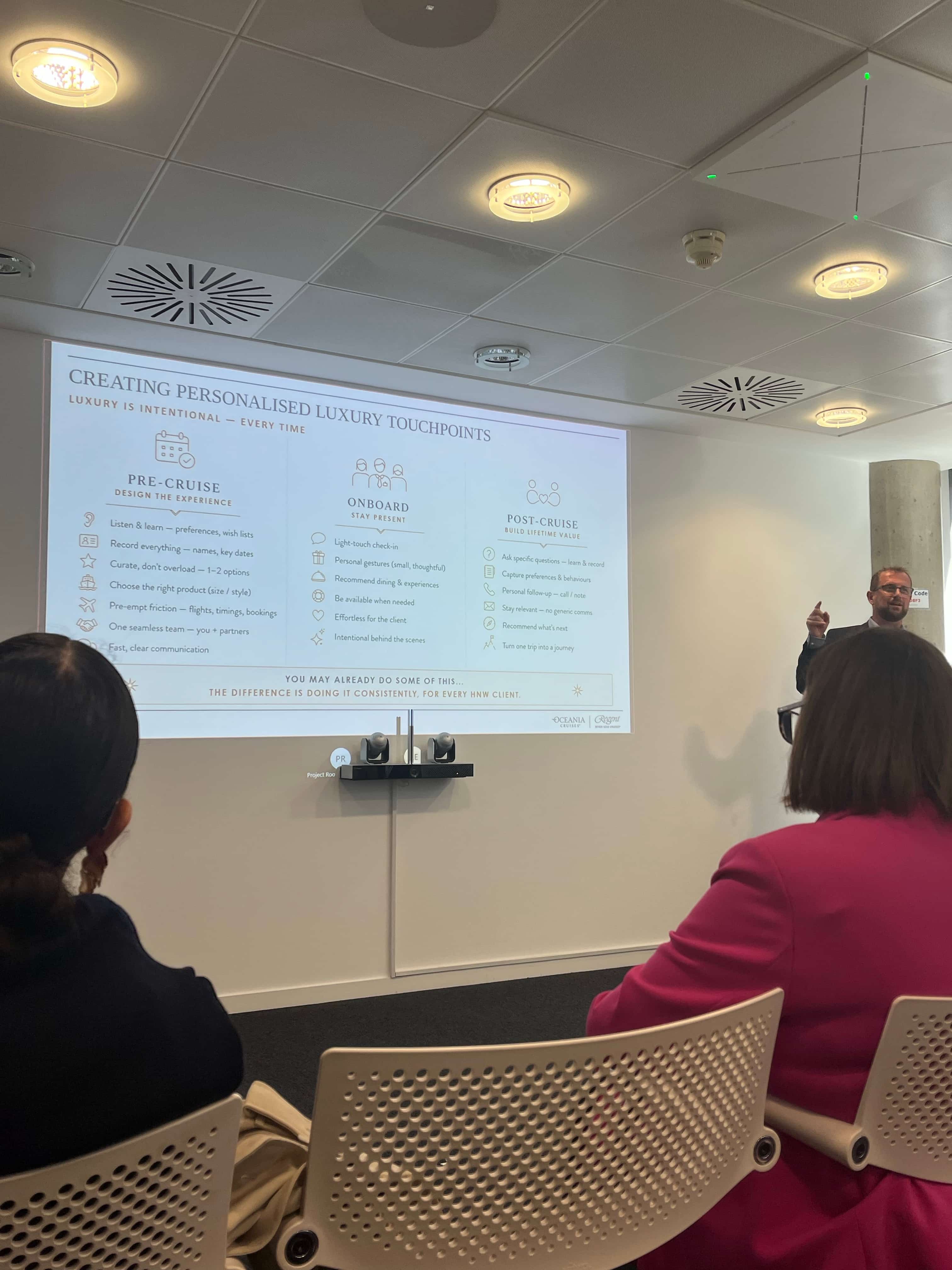 Speaker presenting at a luxury travel seminar, with a slide on personalised luxury touchpoints for pre-cruise, onboard and post-cruise experiences. image