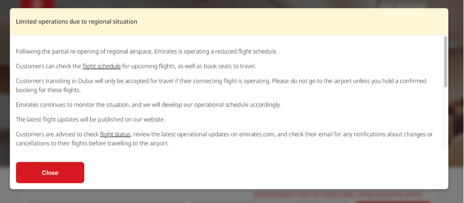 Website pop-up notice from Emirates stating limited operations due to a regional situation, advising travellers of a reduced flight schedule, to check flight status and only go to the airport with a confirmed booking, with a red ‘Close’ button at the bottom. image